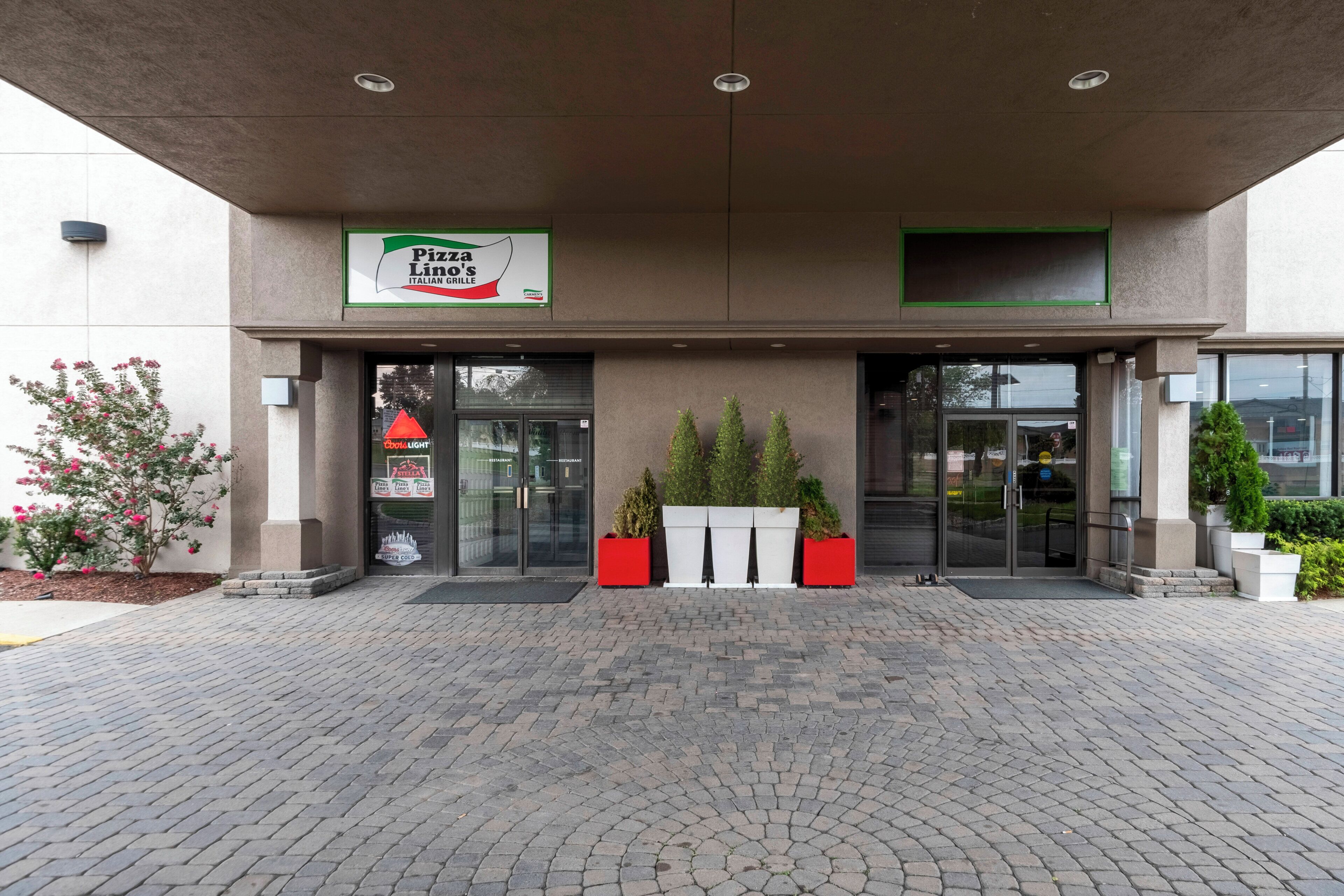 Pizza Lion's Italian Grille met een moderne ingang, plantenbakken en een verharde looppad.