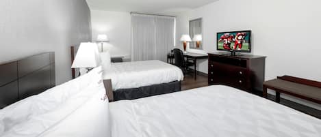 Une chambre d’hôtel avec deux lits, un bureau, une télévision et un banc.