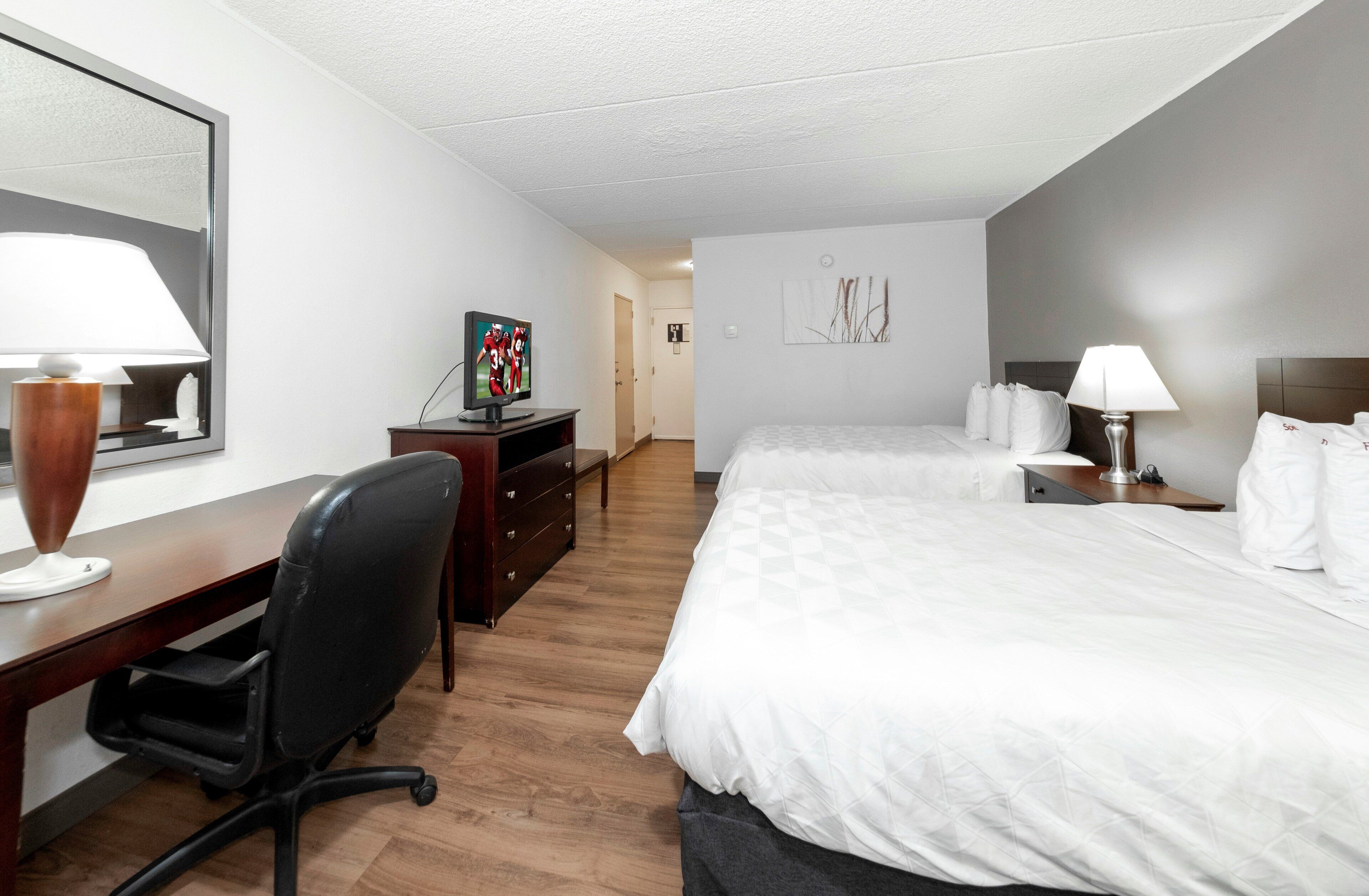 Una habitación de hotel con una cama, un escritorio, una silla, un televisor y una lámpara.