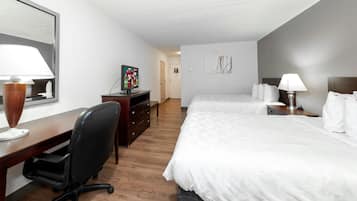 Una habitación de hotel con una cama, un escritorio, una silla, un televisor y una lámpara.