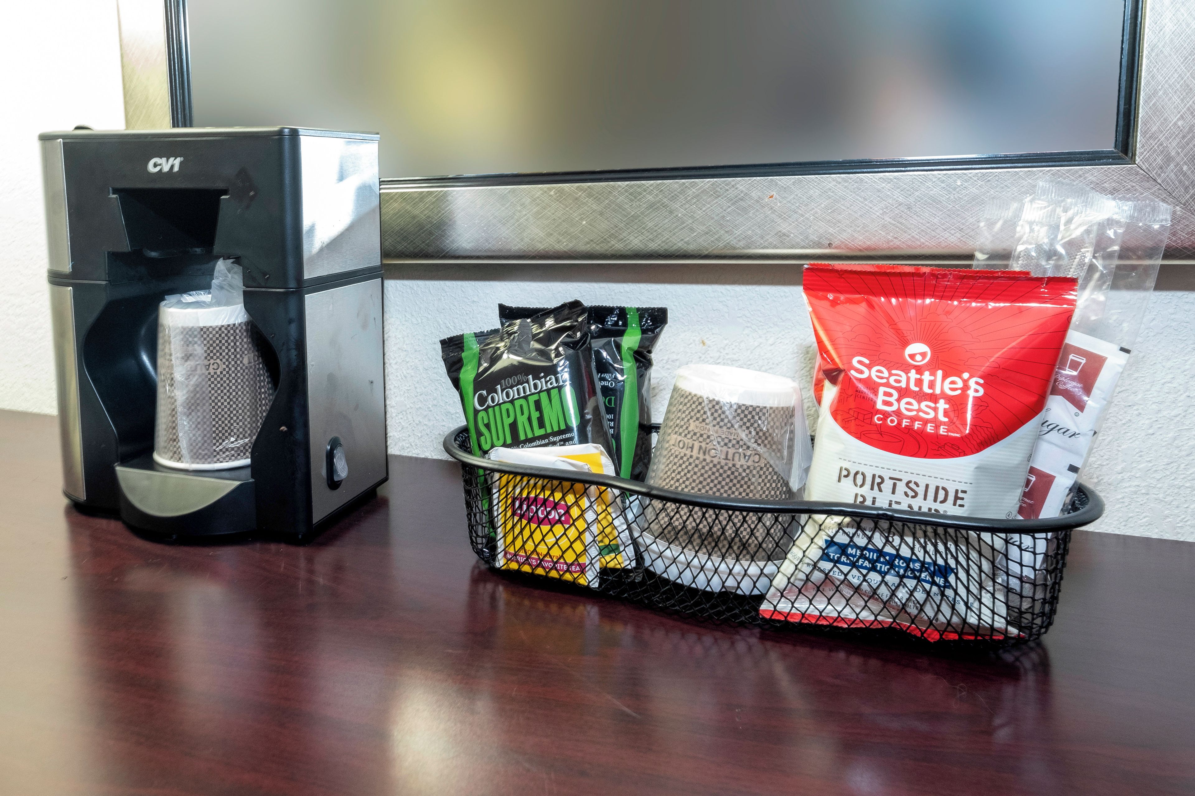 A coffee maker, a basket with coffee pods and a bag of coffee, and a wall with a window.
