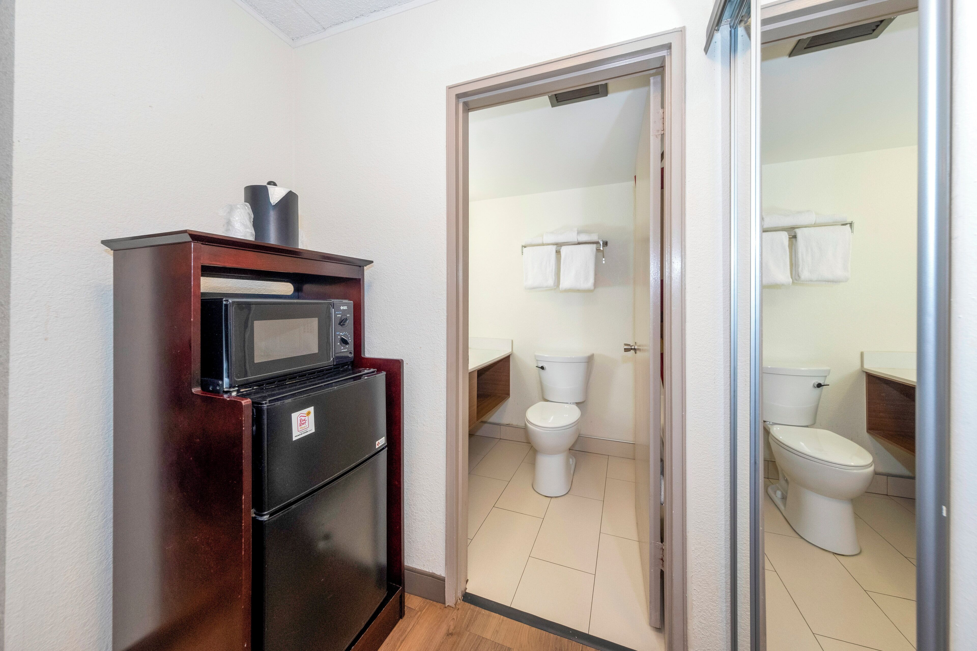 A compact kitchenette with a microwave and refrigerator, a bathroom with two toilets, and a shower area.