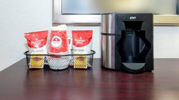 A coffee maker with a water reservoir and a basket containing coffee pods and a packet of coffee creamer.