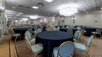 Un salón de conferencias con mesas redondas, sillas y una araña.