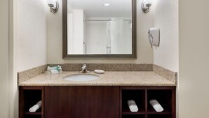 A bathroom with a large mirror, a sink, and a towel rack.