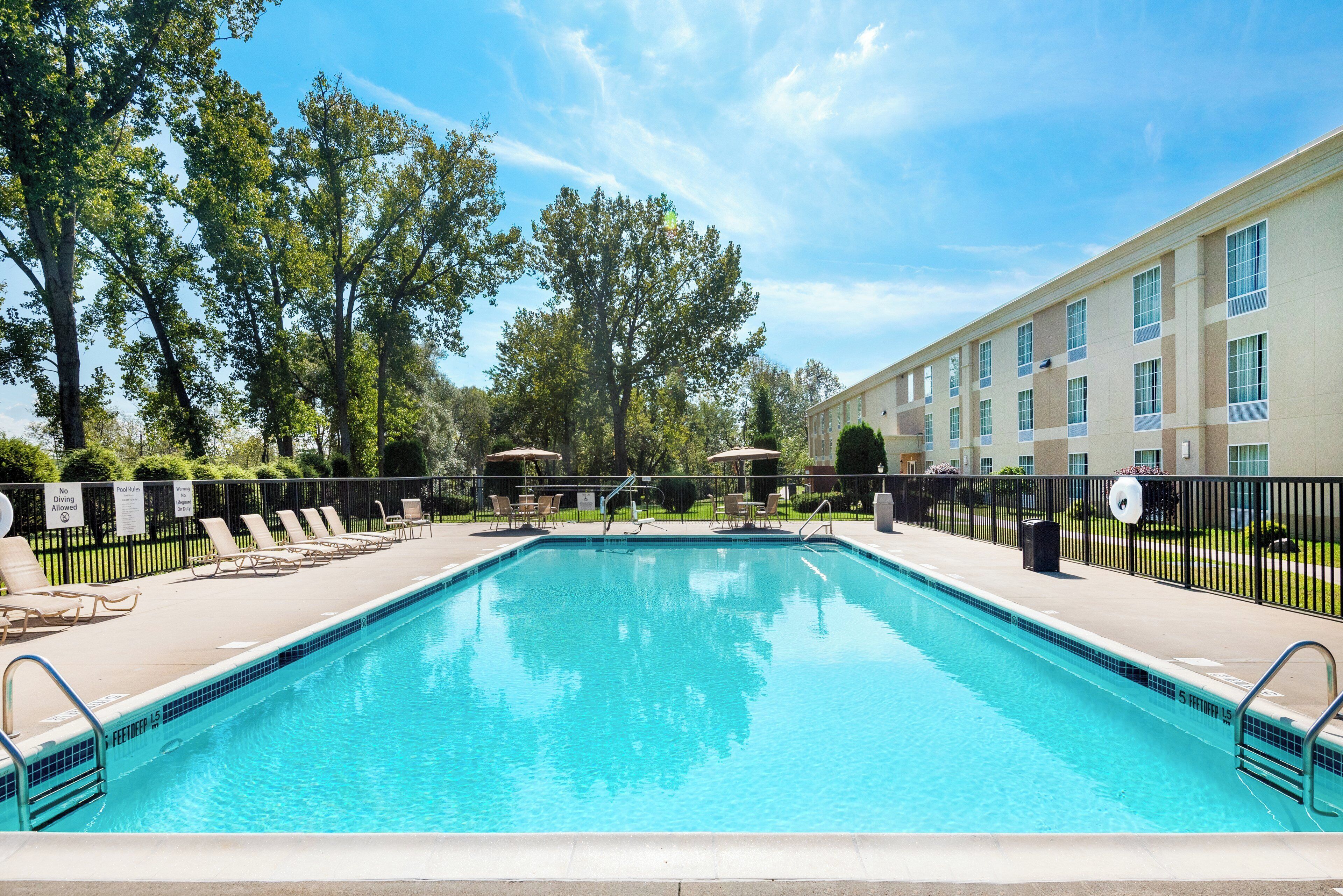 A swimming pool with lounge chairs and a building in the background.