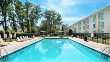 A swimming pool with lounge chairs and a building in the background.