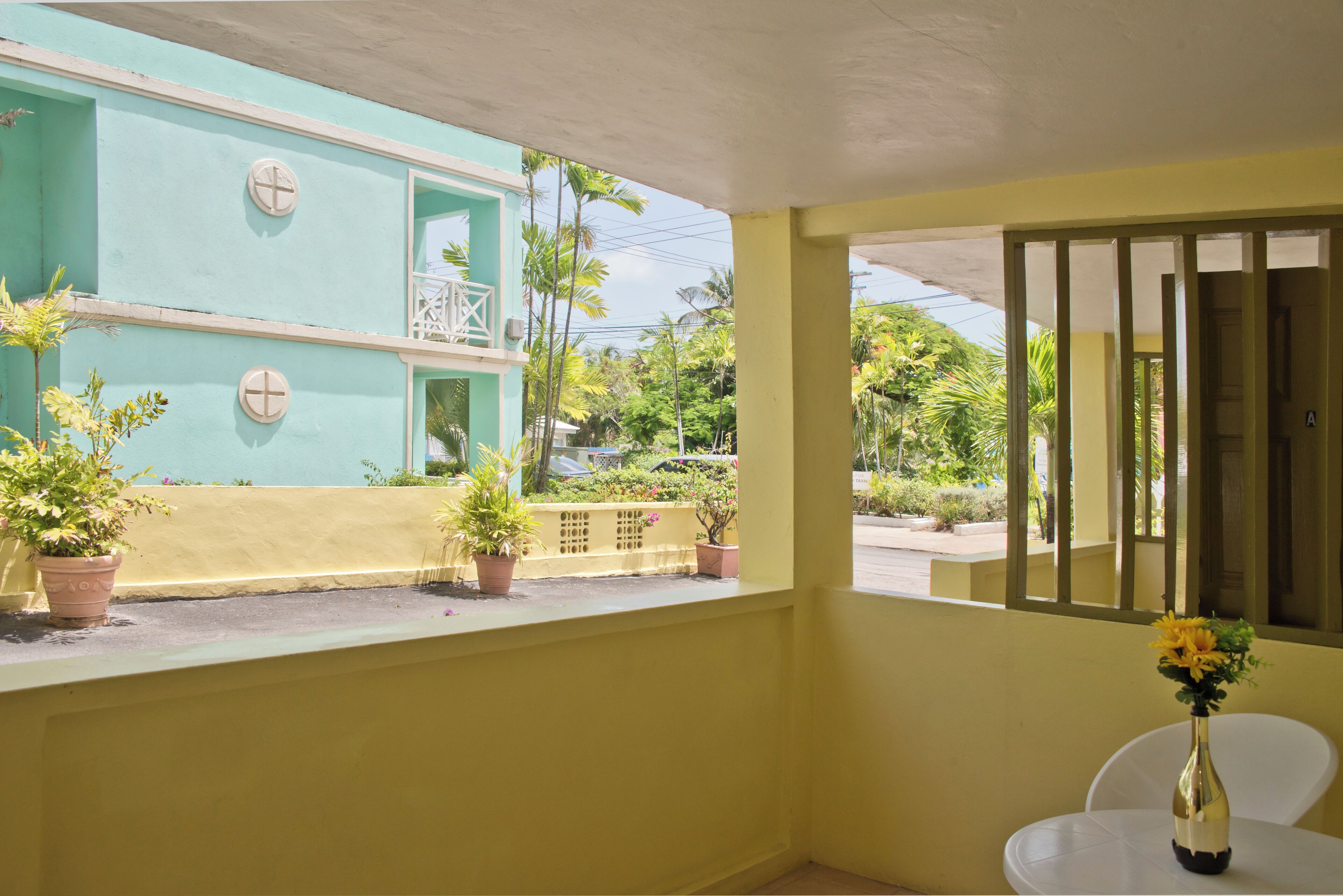 A balcony with potted plants and a table with a vase.
