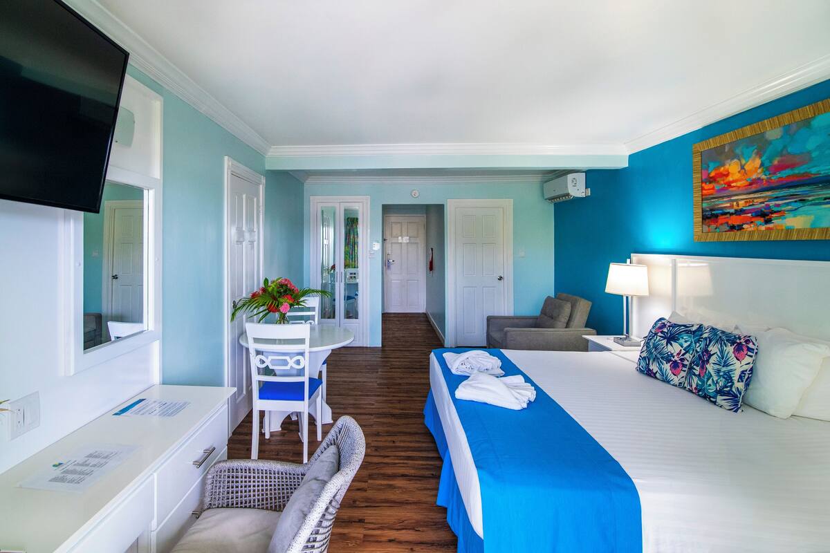 Una habitación de hotel con cama, escritorio, silla, televisión y un cuadro en la pared.