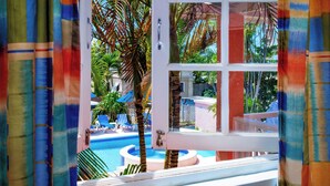 A view of a swimming pool with palm trees, lounge chairs, and a white fence. - Dover Beach Hotel (St. Lawrence Gap)