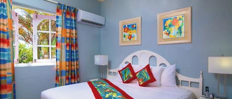 Habitación de hotel con cama, mesita de noche, cortinas en una ventana y dos cuadros colgados en la pared.