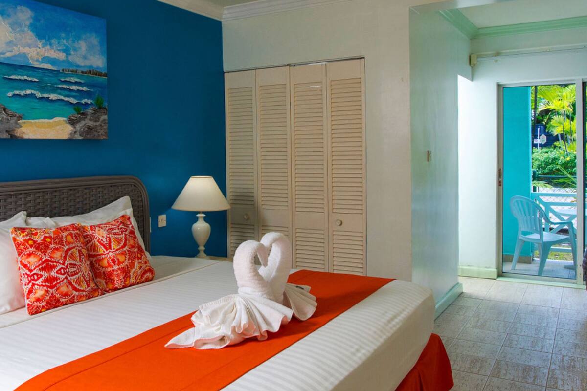 Habitación de hotel con cama, un cuadro de una playa, armario y vistas al exterior.