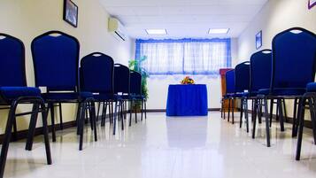 A conference room with rows of blue chairs, a podium, and a table with a blue tablecloth.