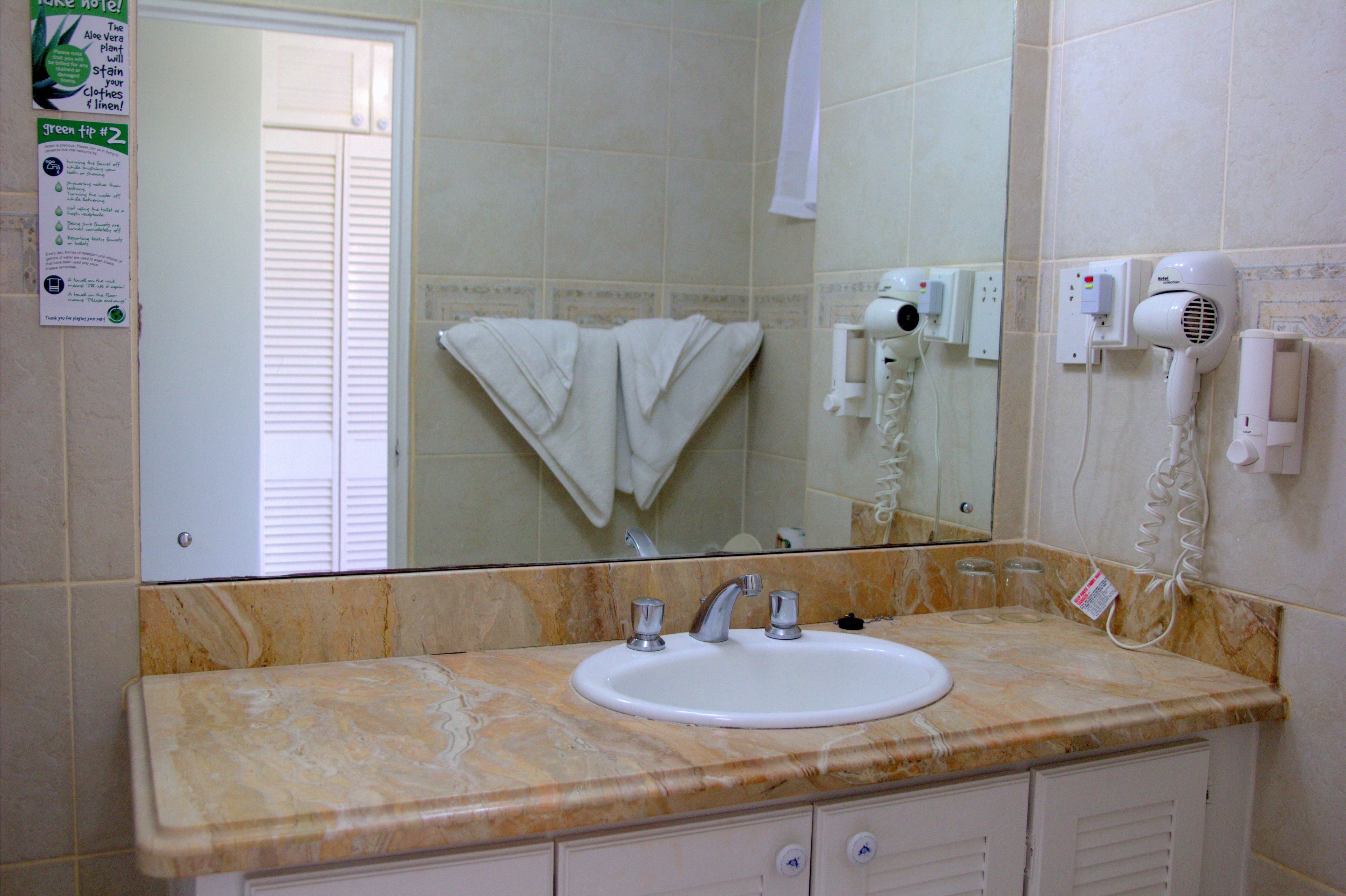 A bathroom with a sink, mirror, towel rack, and hair dryer.