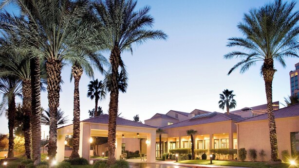 A hotel with a covered outdoor area, palm trees, and a pool. - Courtyard by Marriott Las Vegas Convention Center (Las Vegas)