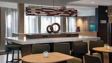A modern hotel lobby with a central island, seating area, and a Starbucks sign.