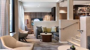 A modern hotel lobby with a sofa, armchairs, a coffee table, and a staircase. - Courtyard by Marriott Las Vegas Convention Center (Las Vegas)