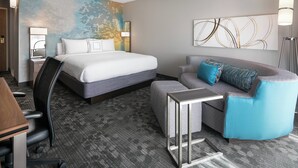A hotel room with a bed, a sofa, a desk, and a chair. - Courtyard by Marriott Las Vegas Convention Center (Las Vegas)