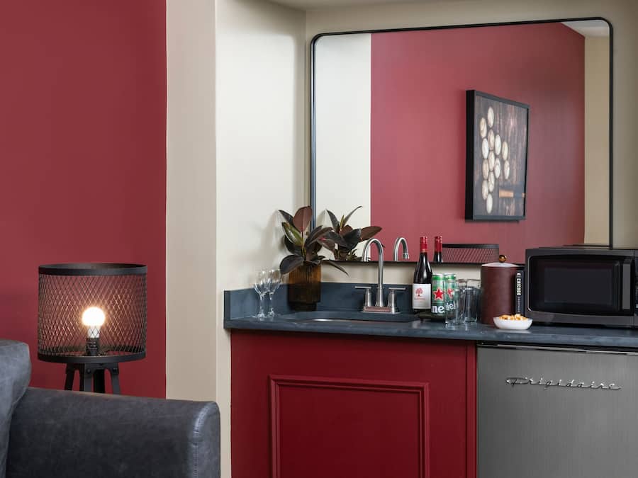 A kitchen with a red cabinet, a sink, a microwave, and a plant on the counter.