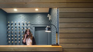 Un espace bar avec un mur en briques bleu foncé, des lambris en bois et un comptoir avec deux chaises.