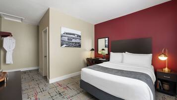 Habitación de hotel con una cama grande, un escritorio, una silla, un armario y una pared de acento roja.