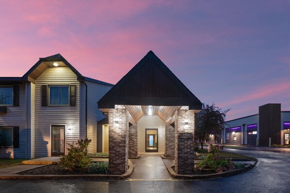 A two-story building with a covered entrance and a brick column. - Travelodge by Wyndham Ishpeming/Marquette (Ishpeming)