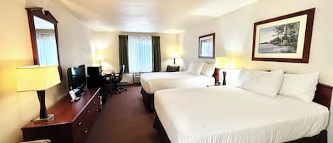 A hotel room with two beds, a desk with a chair, a TV, and a desk lamp.