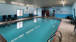 An indoor swimming pool with clear water, surrounded by tiled walls and a ceiling with fluorescent lights. - Travelodge by Wyndham Ishpeming/Marquette (Ishpeming)