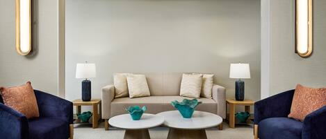 Una sala de estar moderna con un sofá, dos sillones, una mesita de centro y una lámpara.