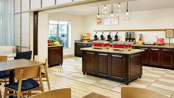 Una cocina moderna con una isla central, armarios de madera oscura y un comedor con sillas y mesa de madera.