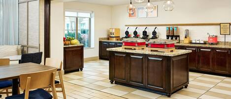 A modern kitchen with a central island, dark wooden cabinets, and a dining area with wooden chairs and a table.