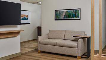 Un salon moderne avec un canapé, une petite table et deux œuvres d’art encadrées accrochées au mur.
