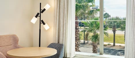 Una habitación de hotel con una cama, una mesa redonda, un sofá y una lámpara de pie.
