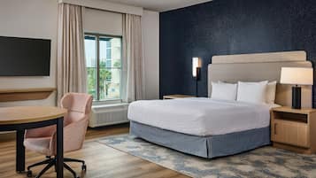 Une chambre d’hôtel comprenant un lit, une table de chevet, une lampe, une chaise et une vue sur l’extérieur.