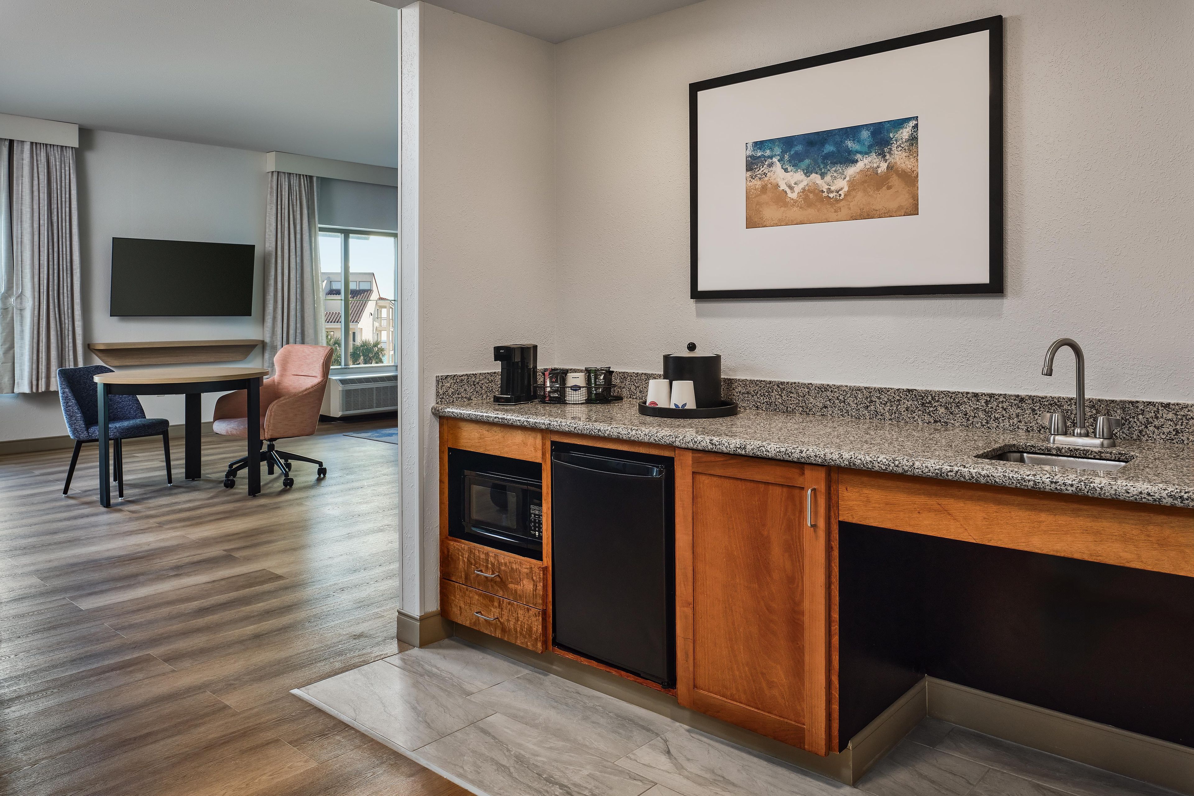 A modern kitchen with a granite countertop, built-in dishwasher, and a coffee maker.