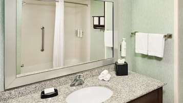 Un baño con un espejo grande, un lavabo, un perchero para toallas y un secador de manos.