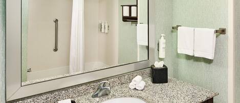 A bathroom with a large mirror, a sink, a towel rack, and a hand dryer.