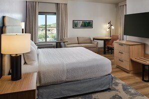 A hotel room with a bed, a desk, a chair, a TV, and a window with curtains. - Hampton Inn & Suites Destin (Destin)