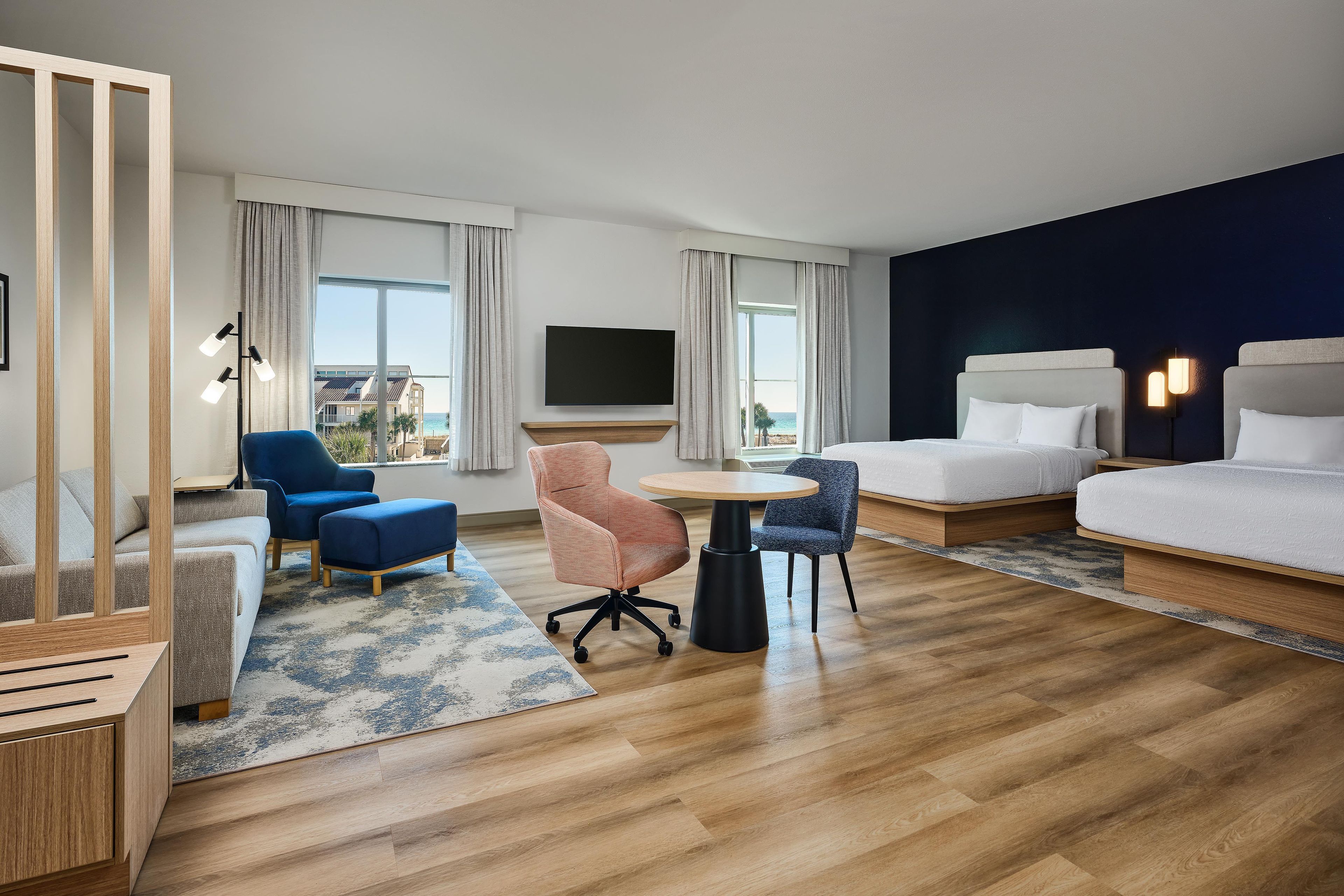Una habitación de hotel con una cama, un escritorio, una silla, un sofá y un televisor.