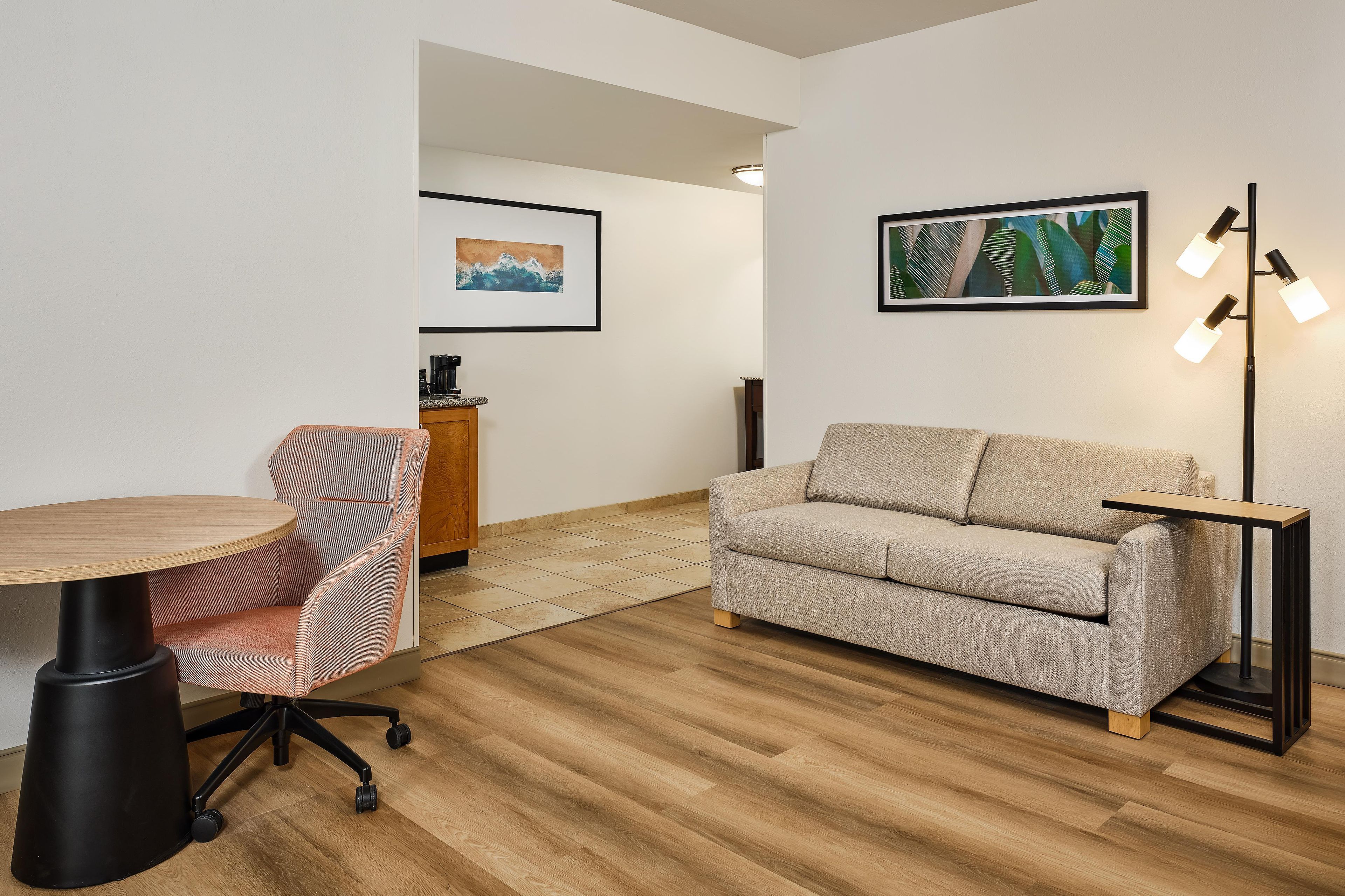 Une pièce moderne avec une table ronde en bois, un fauteuil rembourré, un canapé et un lampadaire.