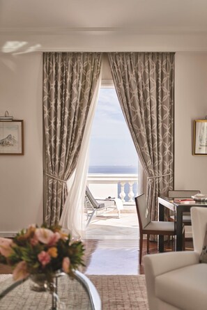 A room with a view of the sea, a dining area with chairs and a table, and a vase with flowers on a table. - Copacabana Palace, A Belmond Hotel, Rio de Janeiro (Rio de Janeiro)