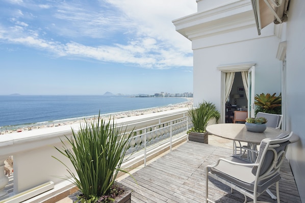 A balcony with a view of the beach, a table with chairs, and potted plants. - Copacabana Palace, A Belmond Hotel, Rio de Janeiro (Rio de Janeiro)