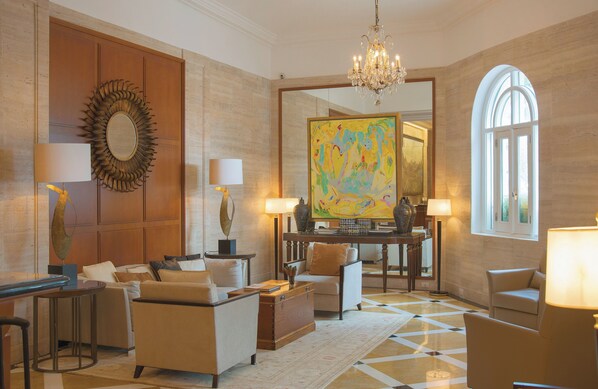A spacious lobby with a chandelier, a large mirror, and a colorful abstract painting.