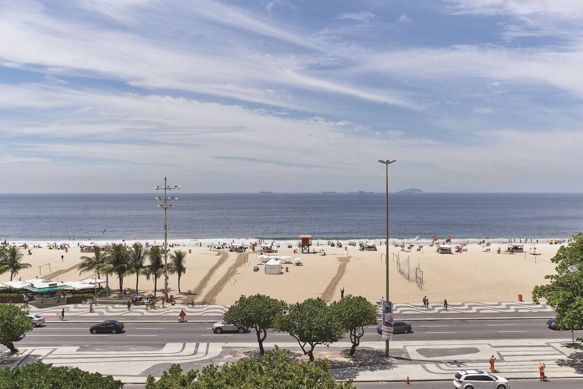 Une plage avec des palmiers, une route et un ciel dégagé.