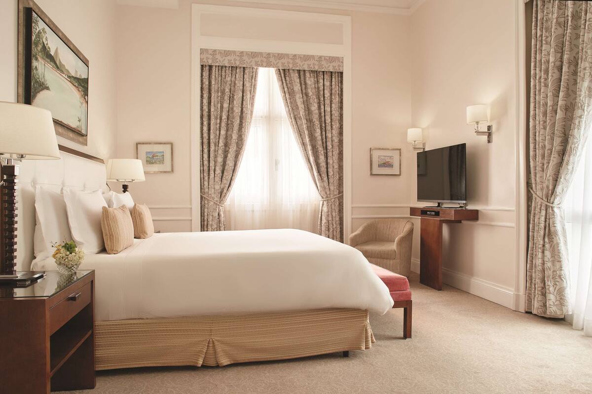 Une chambre d’hôtel avec un grand lit, une télévision, un bureau avec une lampe et une chaise.