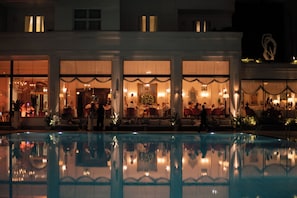 A hotel with multiple dining areas, a swimming pool, and a reflection of the pool in the water. - Copacabana Palace, A Belmond Hotel, Rio de Janeiro (Rio de Janeiro)