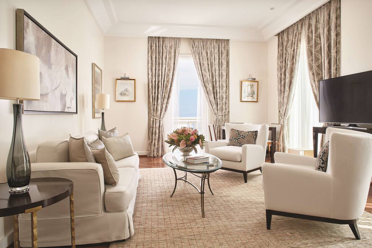 Un salon bien éclairé, avec un canapé, un fauteuil et une table basse sur laquelle est posé un vase.