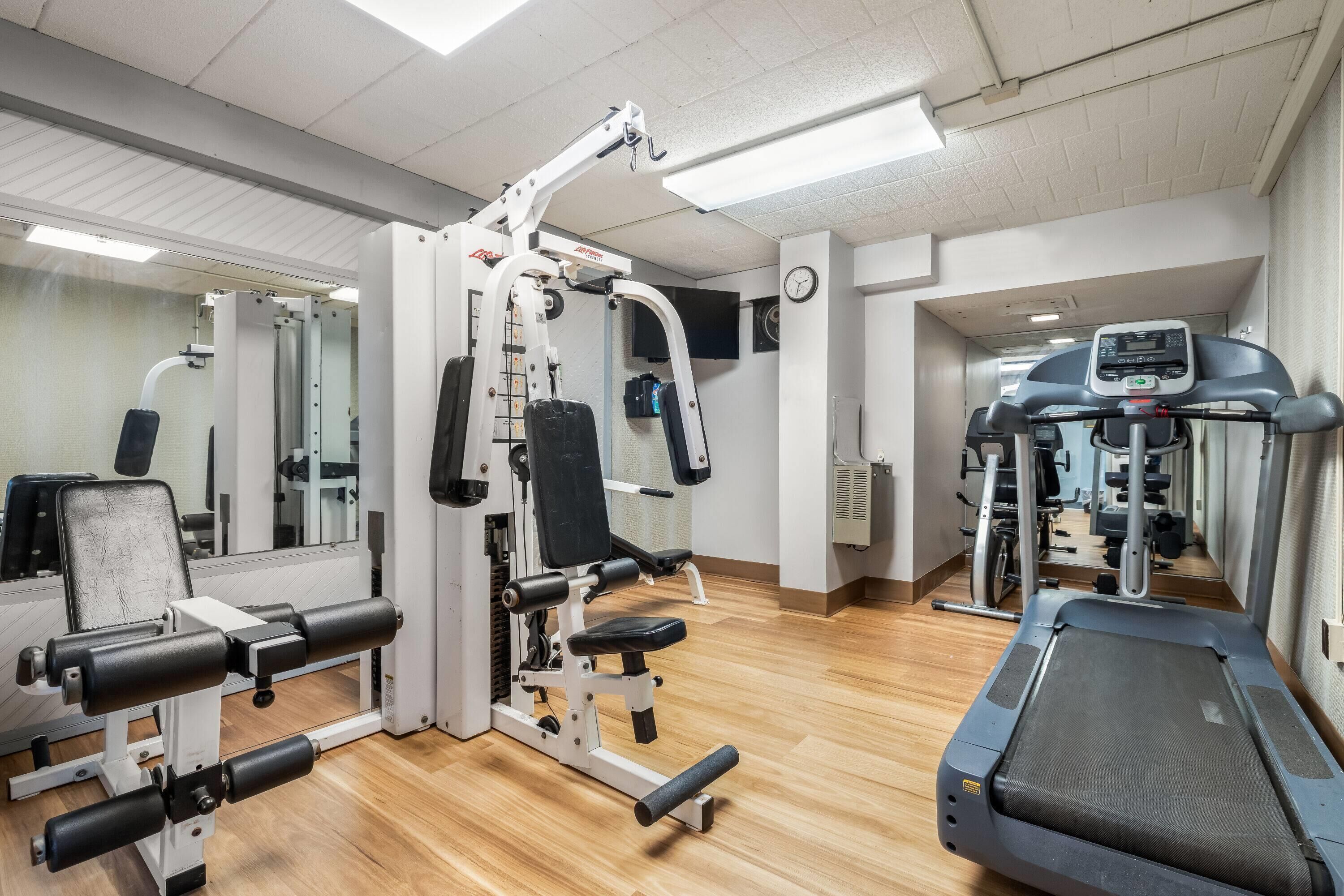 Une salle de sport équipée de matériel d’exercice, d’un tapis de course et d’un miroir.