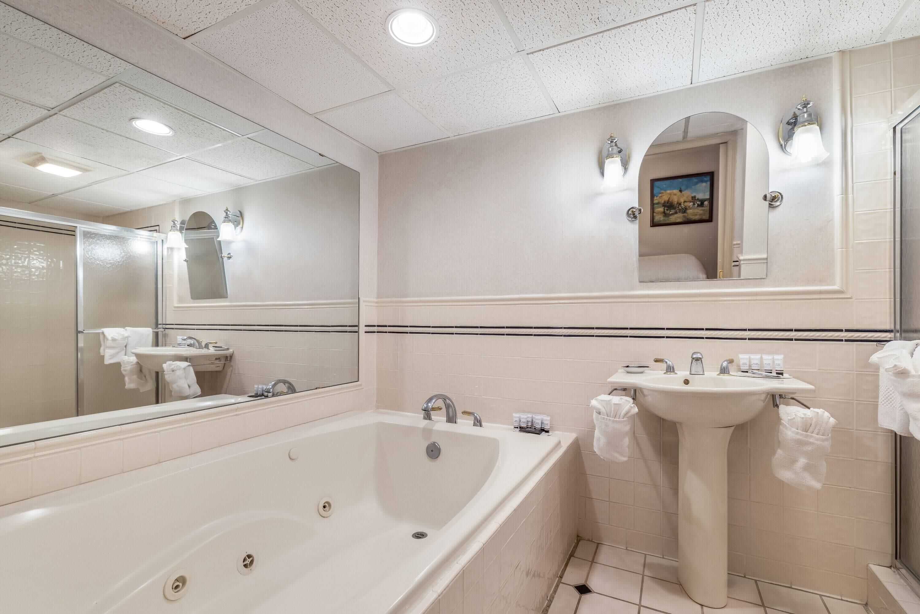 Une salle de bain moderne avec une grande baignoire, un lavabo sur colonne et un miroir au-dessus du lavabo.