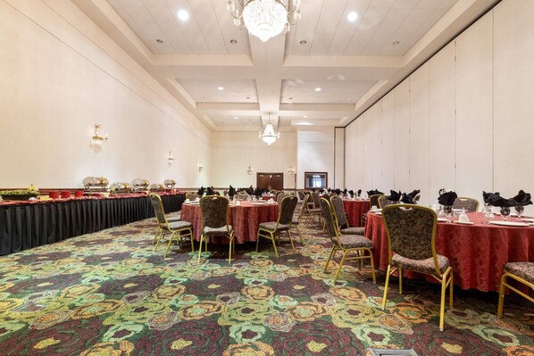 Un salón de banquetes con mesas redondas, sillas y una alfombra estampada.